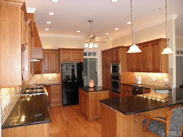7009 Millstone Ridge Court Raleigh, NC 27614 - Photo 6 of 25 a kitchen with stainless steel appliances kitchen island granite countertop a sink refrigerator and cabinets