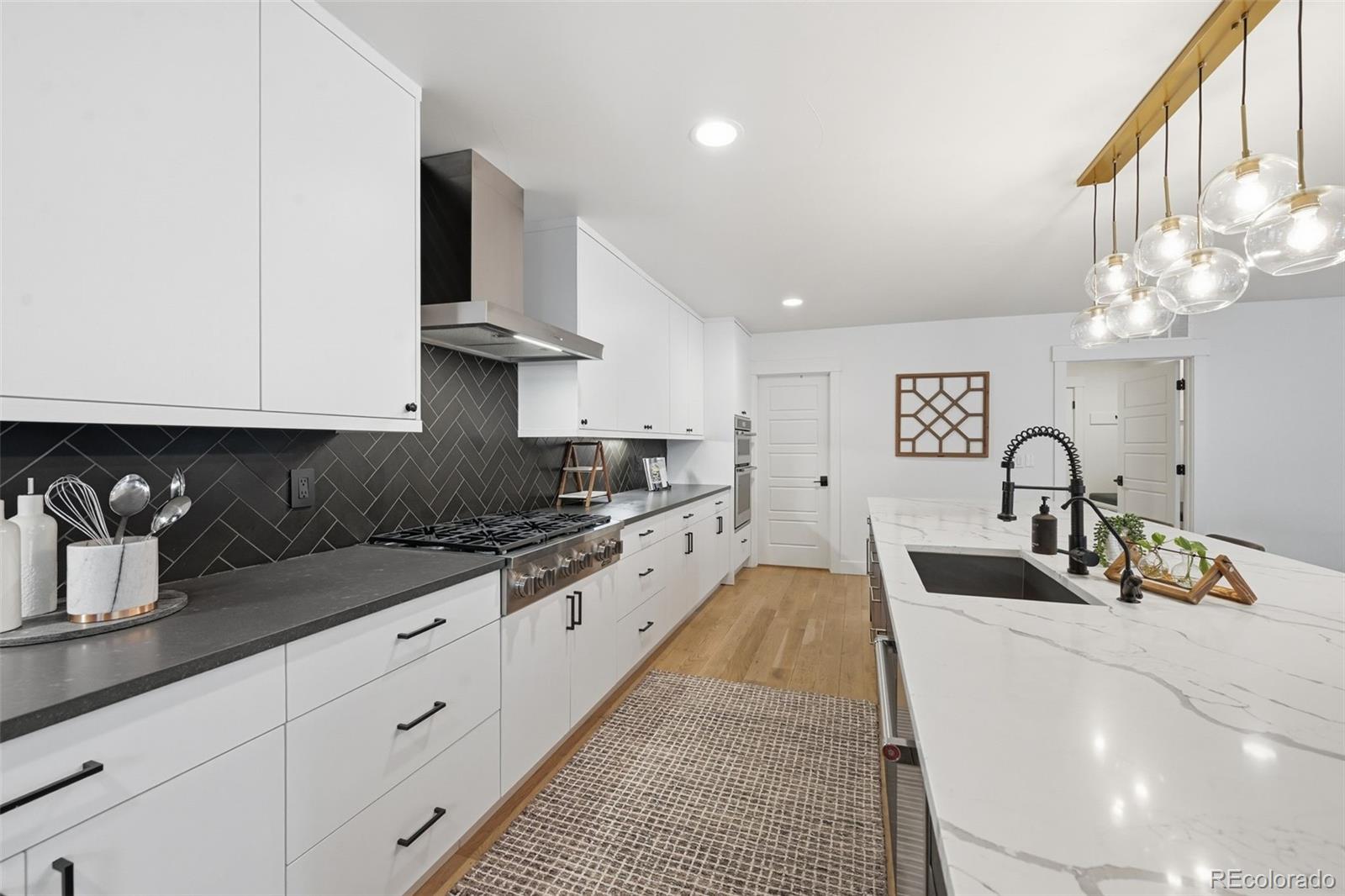 2757 South Steele Street Denver, CO 80210 - Photo 16 of 50 a large kitchen with stainless steel appliances granite countertop a sink dishwasher a stove and white cabinets with wooden floor