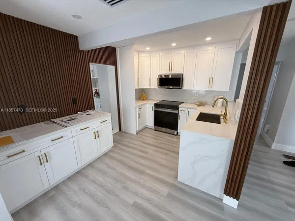 a large kitchen with stainless steel appliances kitchen island granite countertop a stove a sink and a refrigerator