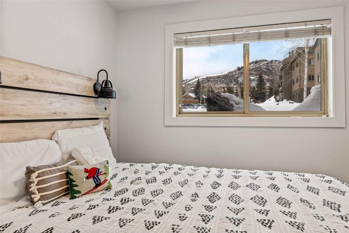 1565 Shadow Run Frontage, Unit B103 Steamboat Springs, CO 80487 - Photo 12 of 28 a bedroom with a bed and a painting on the wall