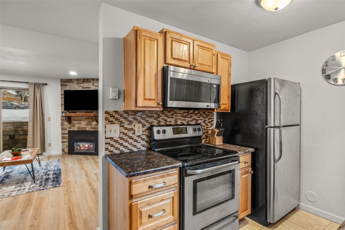 1565 Shadow Run Frontage, Unit B103 Steamboat Springs, CO 80487 - Photo 7 of 28 a kitchen with granite countertop a refrigerator stove and microwave