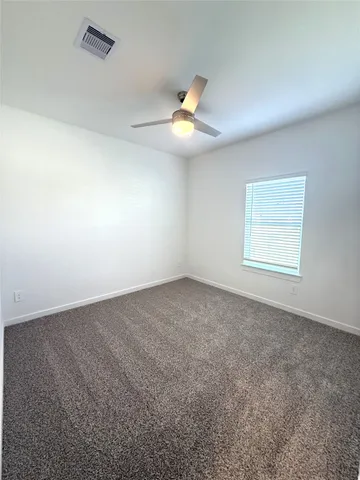 an empty room with a ceiling fan and window