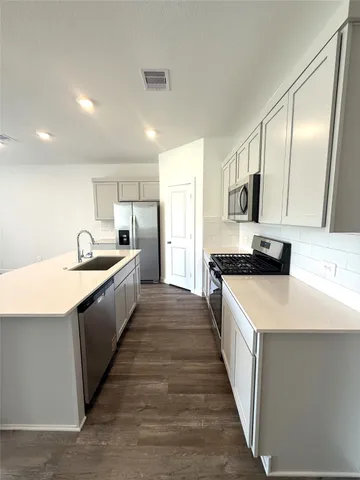 a large kitchen with stainless steel appliances kitchen island granite countertop a sink and dishwasher a stove with wooden floor