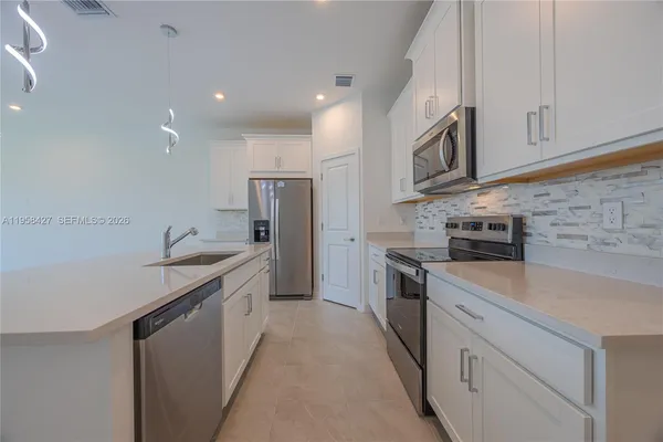 a kitchen with stainless steel appliances granite countertop a sink a stove and a refrigerator