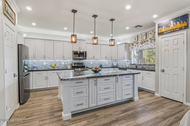 a kitchen with stainless steel appliances granite countertop a sink a stove and a wooden floors