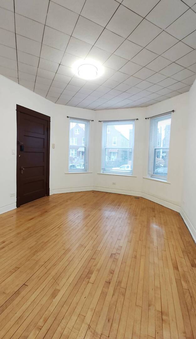 3137 West 42nd Street, Unit 1 Chicago, IL 60632 - Photo 2 of 7 an empty room with wooden floor and windows