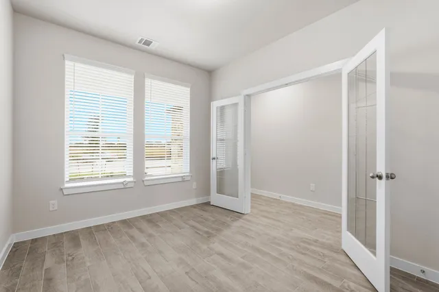 a view of an empty room with wooden floor and a window