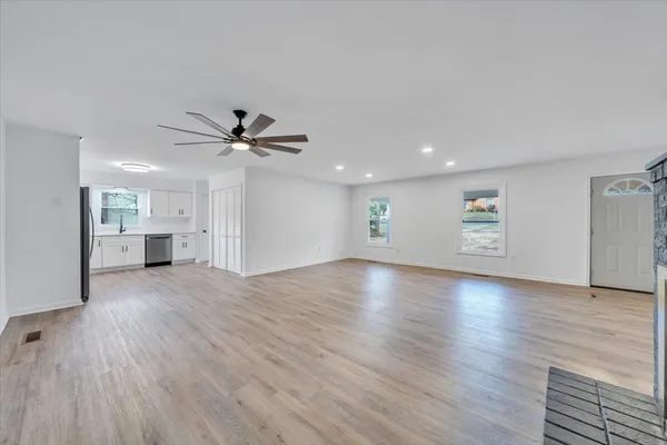 a view of empty room with wooden floor and fan