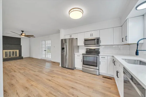 a view of a livingroom with wooden floor a fireplace and entryway