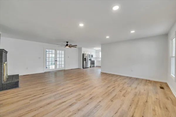 a view of an empty room with window and wooden floor