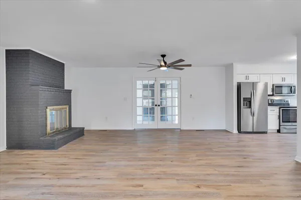 a view of an empty room with a window and wooden floor
