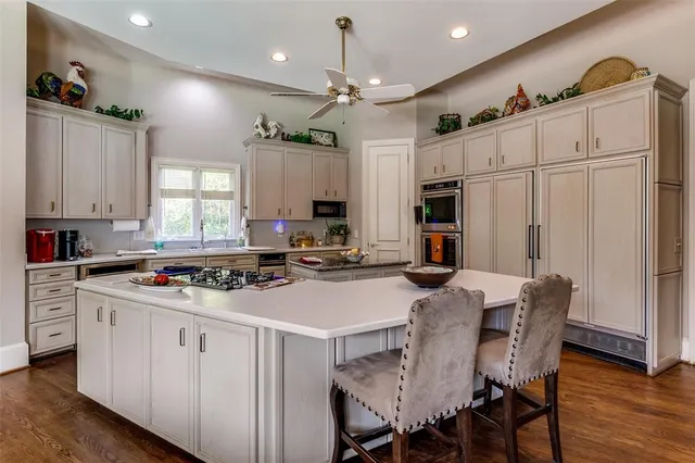 a kitchen with stainless steel appliances a stove sink refrigerator dining table and chairs