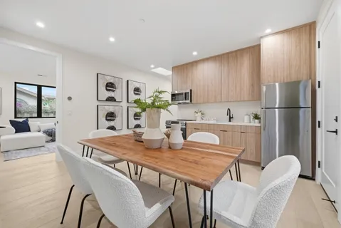 a kitchen with a dining table chairs and refrigerator