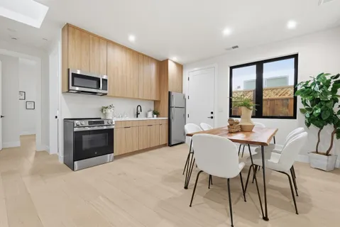 a kitchen with stainless steel appliances a stove a sink a microwave a dining table and chairs