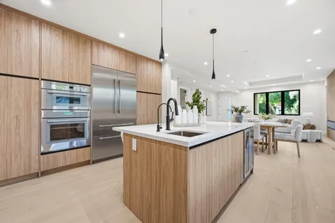 a kitchen with stainless steel appliances kitchen island a table chairs in it and wooden floors