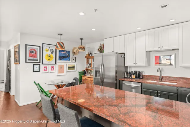 a dining hall with stainless steel appliances granite countertop a dining table and chairs