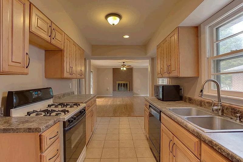 4974 Princeton Road Memphis, TN 38117 - Photo 6 of 10 Kitchen featuring white gas range oven, light brown cabinetry, stainless steel dishwasher, black microwave, and light tile patterned floors