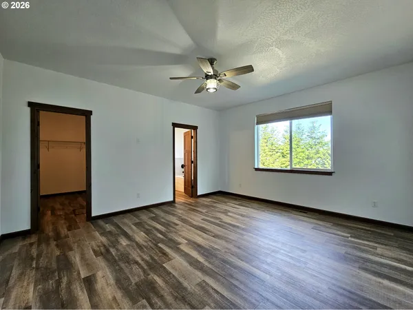 an empty room with wooden floor ceiling fan and windows