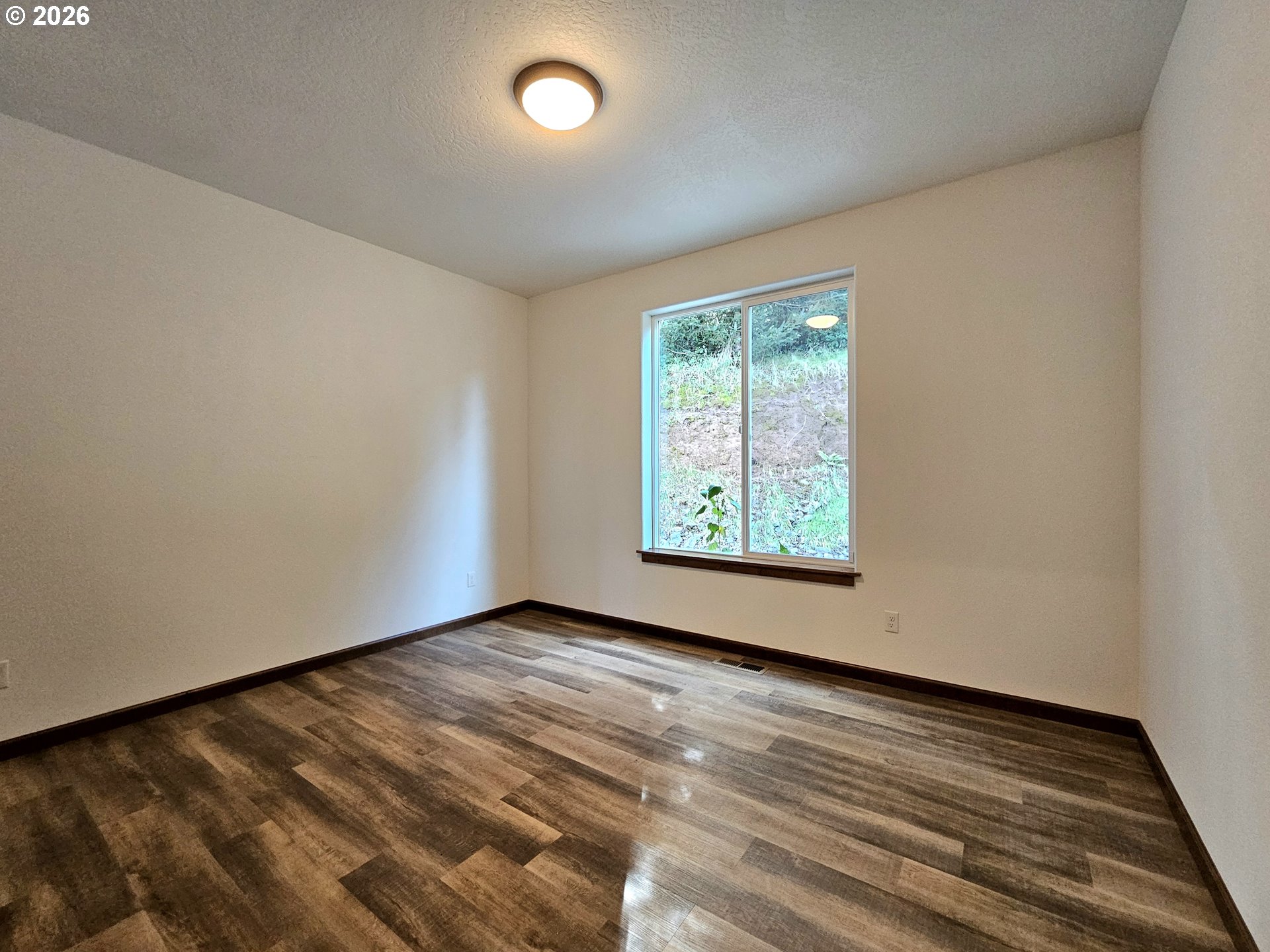 98205 Sunforest Court Brookings, OR 97415 - Photo 26 of 45 an empty room with wooden floor and windows