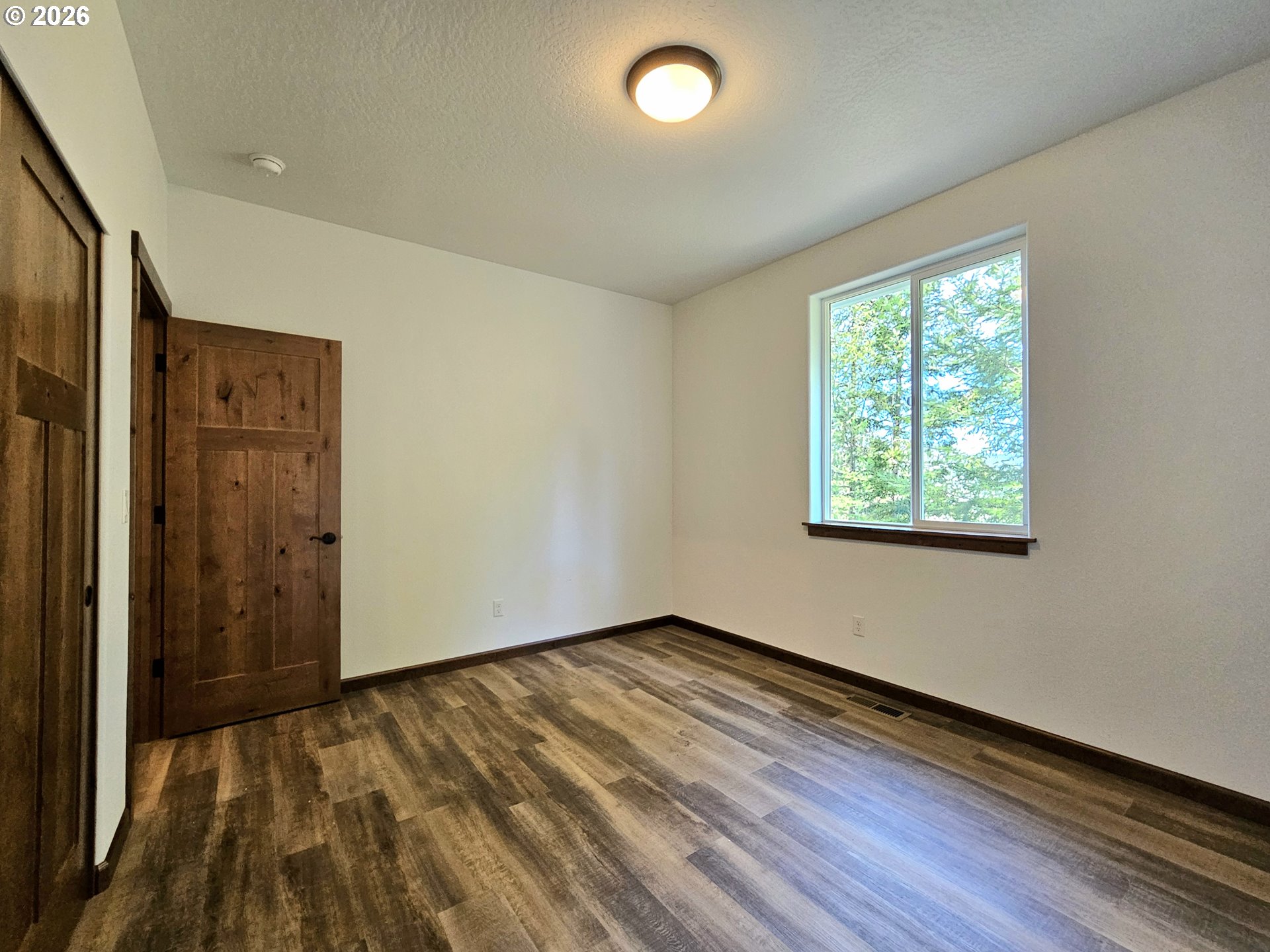 98205 Sunforest Court Brookings, OR 97415 - Photo 27 of 45 an empty room with wooden floor and windows
