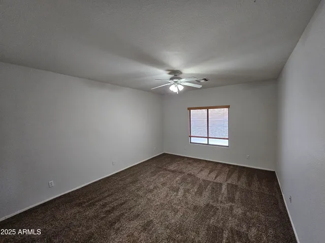 an empty room with a ceiling fan and a window