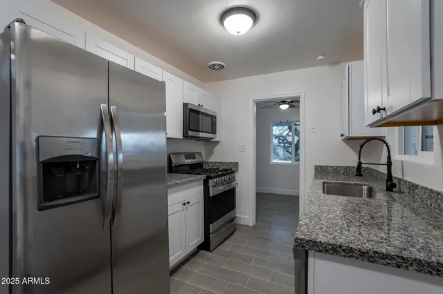a kitchen with stainless steel appliances granite countertop a sink stove and refrigerator