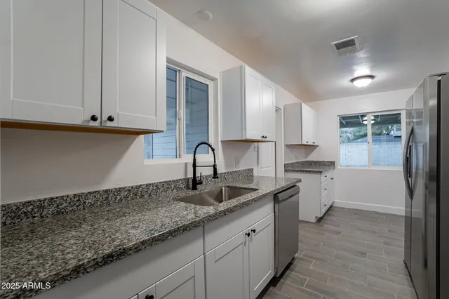 a kitchen with granite countertop white cabinets and sink