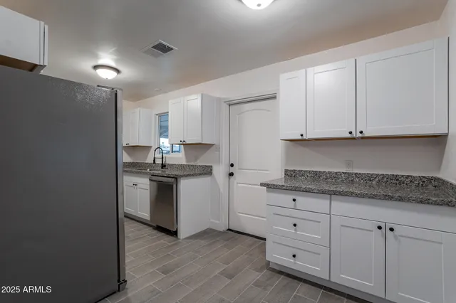 a kitchen with granite countertop white cabinets and stainless steel appliances