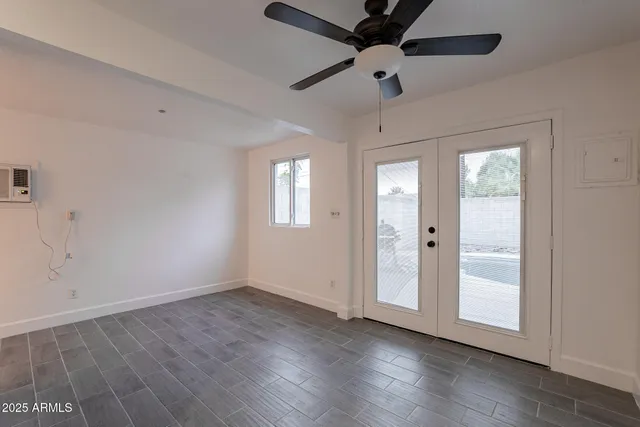 a view of an empty room with a window and wooden floor