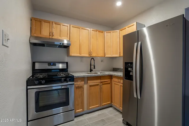 a kitchen with stainless steel appliances granite countertop a stove a refrigerator and a window