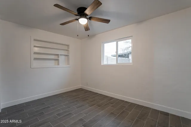 an empty room with wooden floor ceiling fan and windows