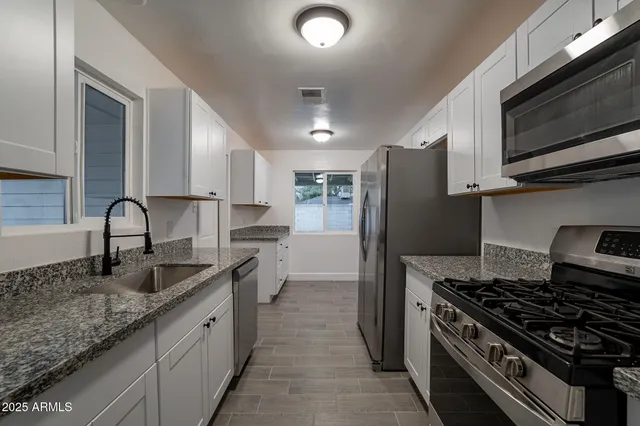 a kitchen with granite countertop a sink stove and refrigerator