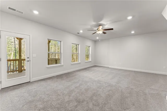 an empty room with chandelier fan and windows