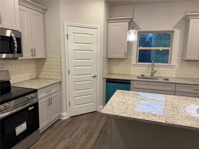 a kitchen with granite countertop a sink cabinets and stainless steel appliances