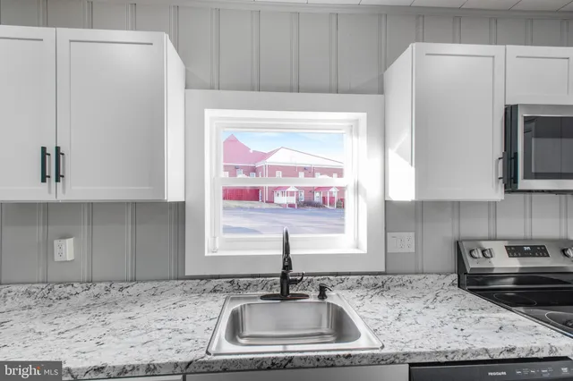 a kitchen with stainless steel appliances granite countertop a sink a refrigerator and a stove