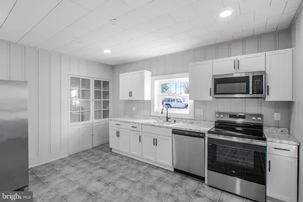 a kitchen with granite countertop a stove sink and microwave