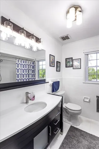 a bathroom with a sink a toilet a mirror and a window