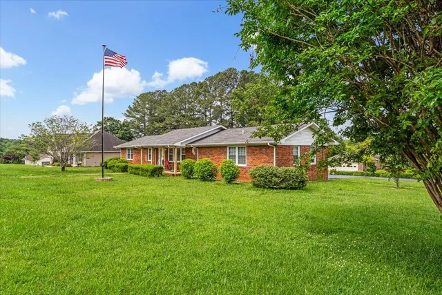 a view of a big house with a big yard and potted plants and large trees