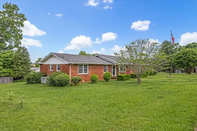 a view of a house with a big yard and large trees