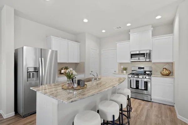 a kitchen with stainless steel appliances granite countertop a kitchen island hardwood floor and a sink