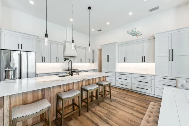 a kitchen with stainless steel appliances kitchen island granite countertop a table chairs sink and cabinets