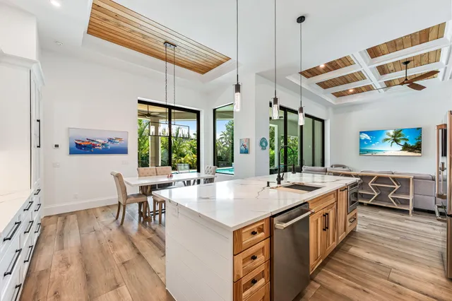 a open kitchen with stainless steel appliances granite countertop a stove top oven a dining table and chairs with wooden floor