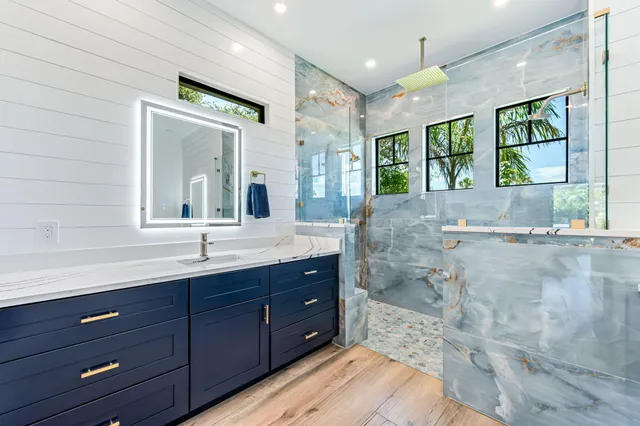 a bathroom with a granite countertop sink mirror and shower