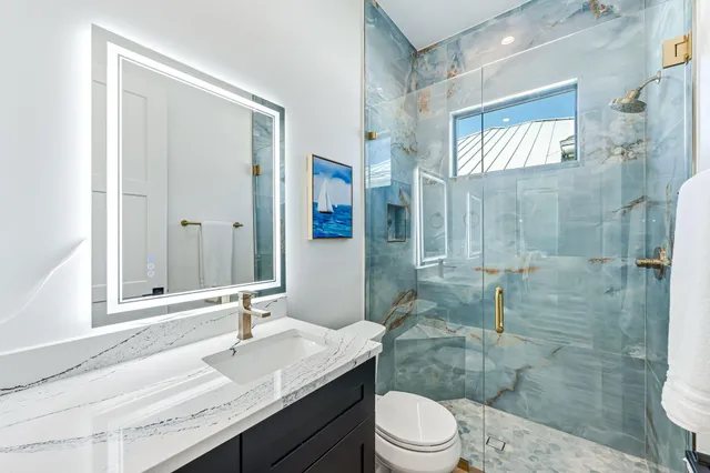 a bathroom with a granite countertop sink toilet a mirror and shower
