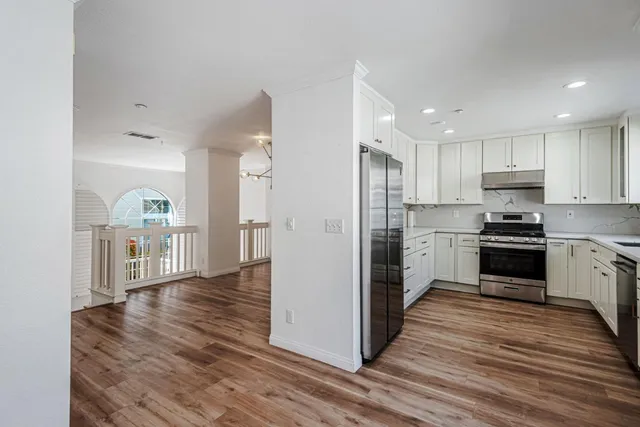 a view of a kitchen with a refrigerator a stove top oven and cabinets