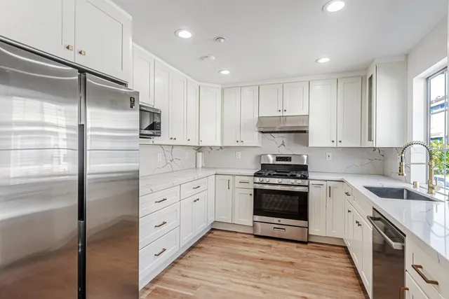 a kitchen with cabinets stainless steel appliances and a window