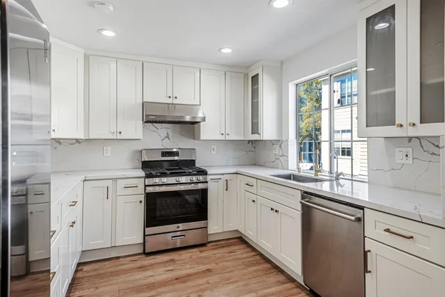 a kitchen with stainless steel appliances granite countertop a stove a sink and white cabinets