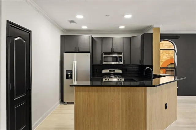 a kitchen with stainless steel appliances granite countertop a sink a stove and a refrigerator