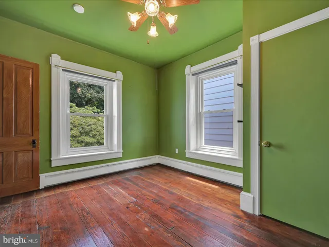 an empty room with wooden floor closet and windows