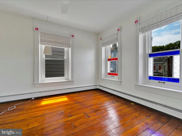 a view of an empty room with window and wooden floor
